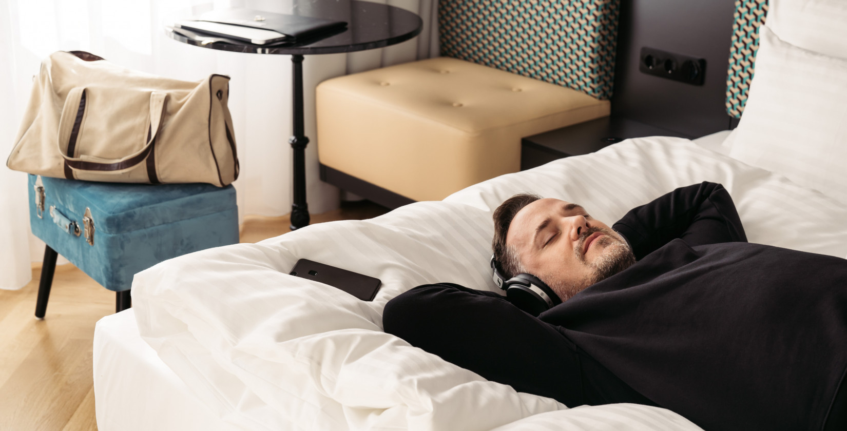 Man lies in bed with headphones on and relaxes