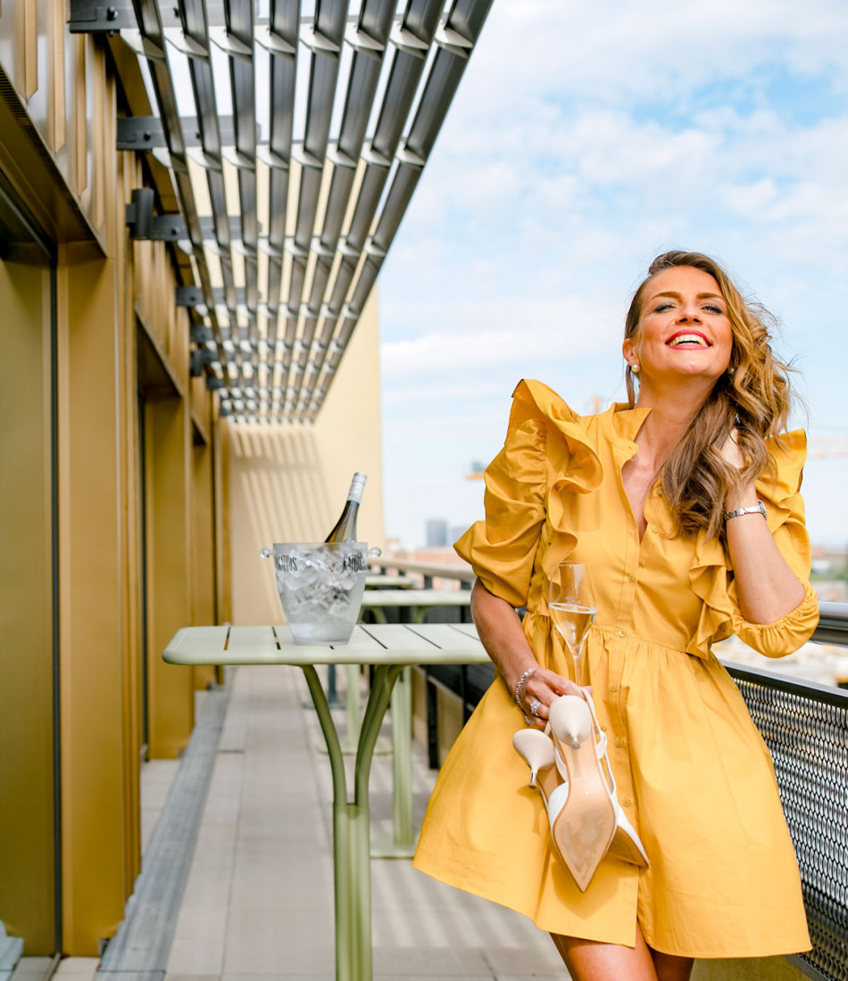 Lächelnde Frau im gelben Kleid auf der Terrasse in Schani's Rooftop