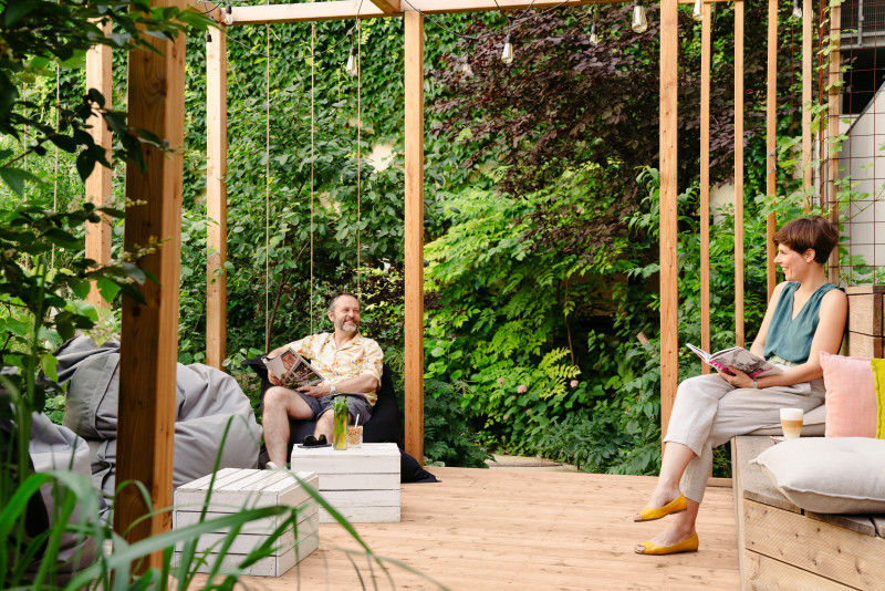 Man and woman sitting and reading in pergola in Schani's garden 