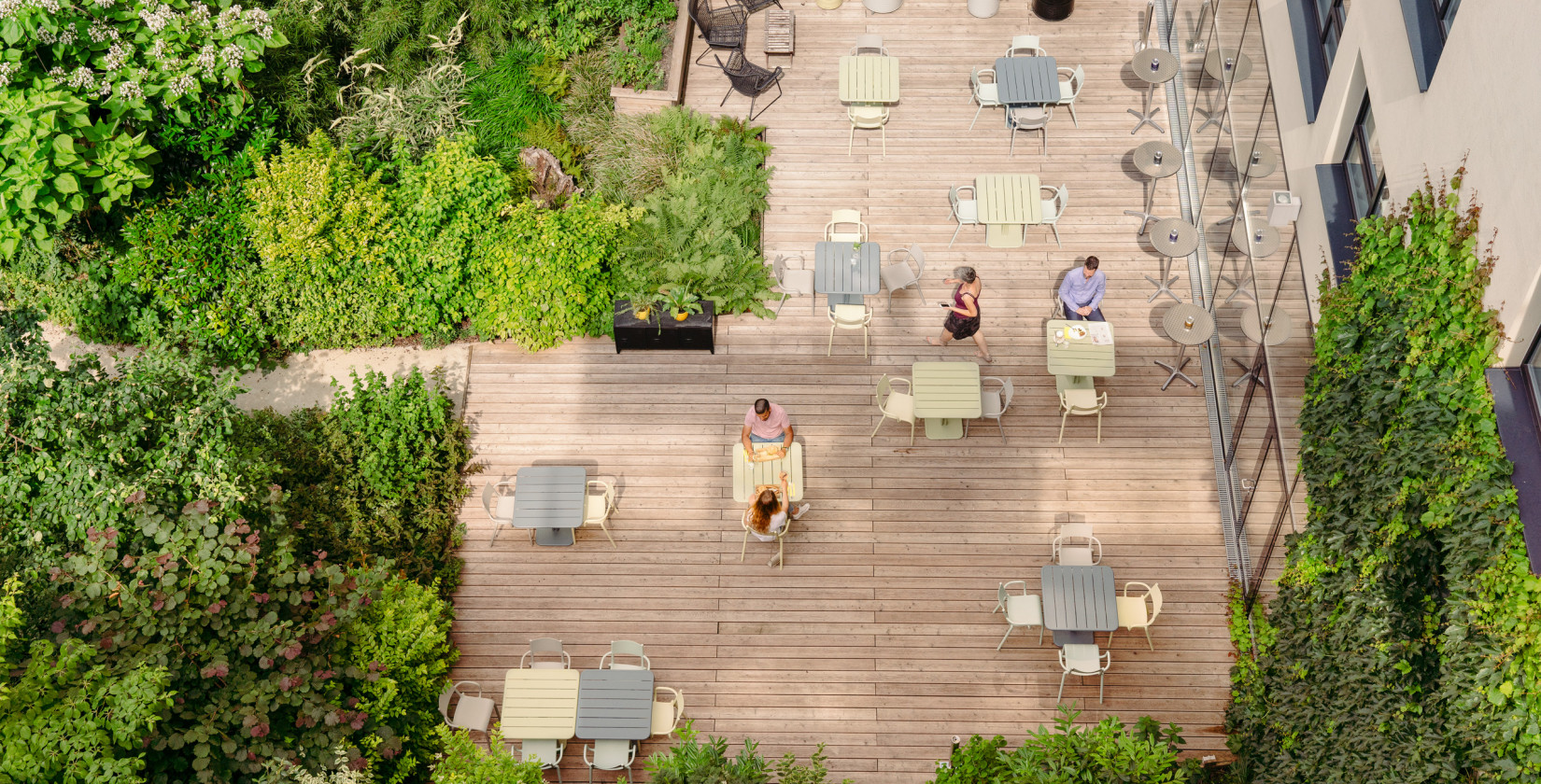 Wooden terrace with metal tables and colorful chairs taken from bird's eye view
