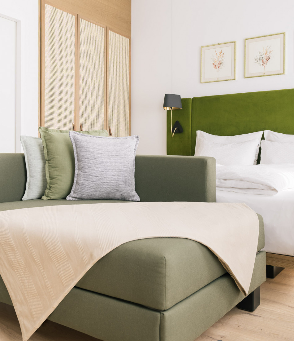 Bequemes Seitenschläfer Sofa vor einem Doppelbett eines Smart Studio Zimmers im Bio-Hotel in Wien