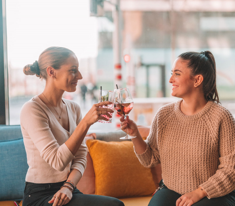 Zwei Frauen stoßen mit Cocktails in der Hotelbar in Wien an